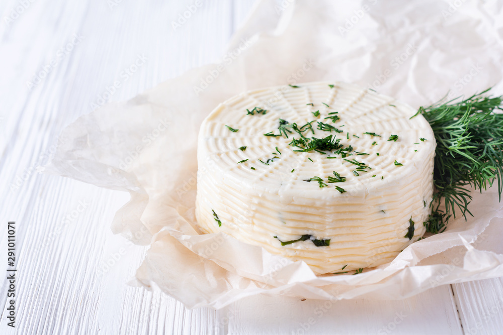 Pickled cheese with dill, spices and garlic on a white wooden background. Selective focus