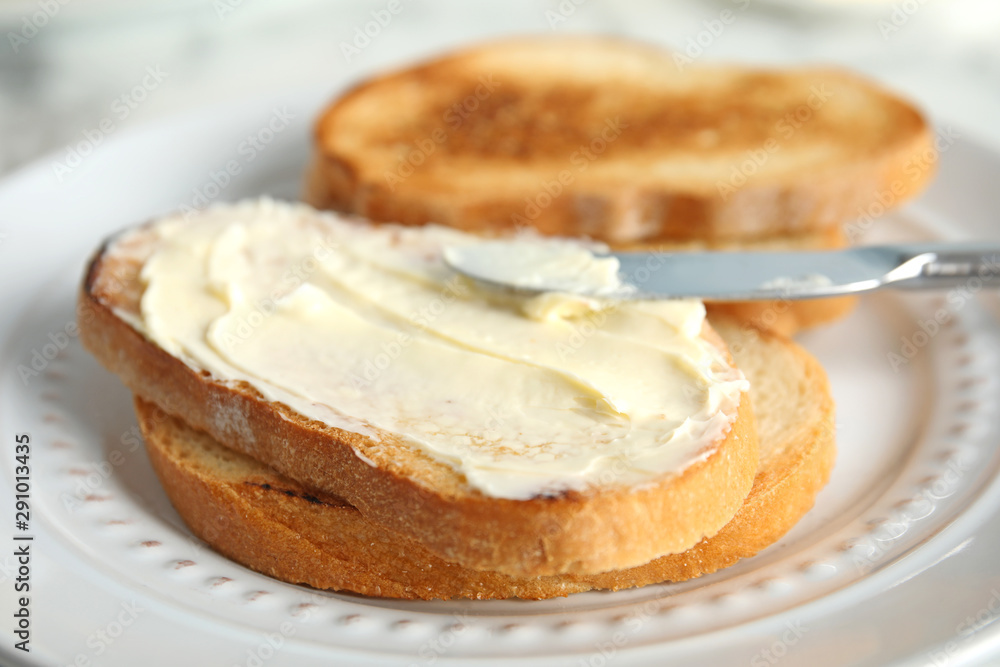 Tasty bread with butter and knife on plate, closeup Tasty bread with butter and knife on plate, closeup