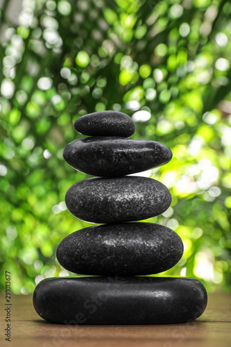 Table with stack of stones and blurred green leaves on background. Zen concept