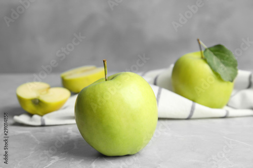 Fresh ripe green apples on grey stone table against blue background, space for text