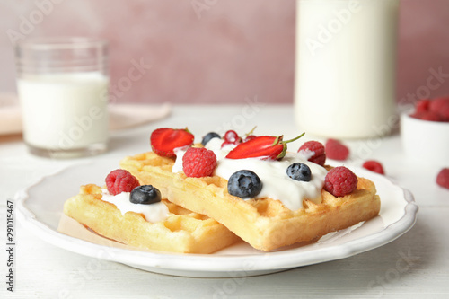 Delicious waffles with fresh berries served on white wooden table against pink background