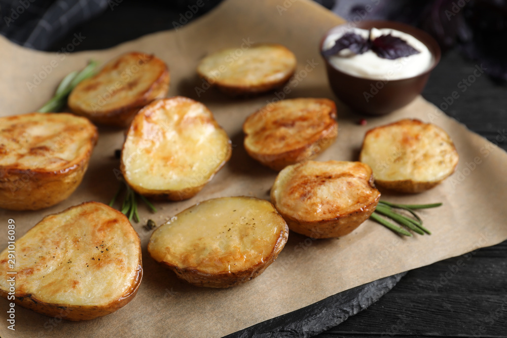 Delicious potato wedges with sour cream on black wooden table, closeup Delicious potato wedges with sour cream on black wooden table, closeup