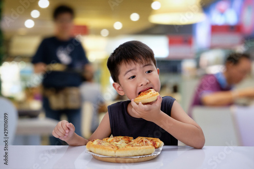 Asian boy is happy to eating pizza with a hot cheese melt stretc photo