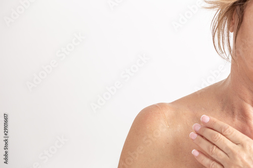 Fotografia view of neck and shoulder of a woman applying lotion isolated on white background