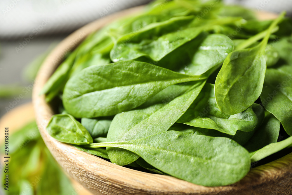 Fresh green healthy spinach in wooden bowl, closeup Fresh green healthy spinach in wooden bowl, closeup