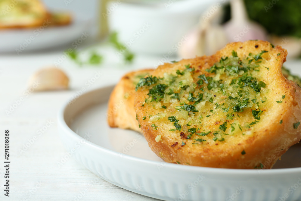 Slices of toasted bread with garlic and herbs on white wooden table, closeup