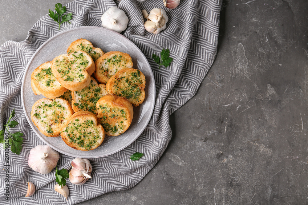 Slices of toasted bread with garlic and herbs on grey table, flat lay. Space for text Slices of toasted bread with garlic and herbs on grey table, flat lay. Space for text