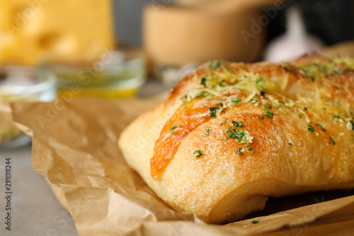 Tasty homemade garlic bread with cheese and herbs on table, closeup. Space for text