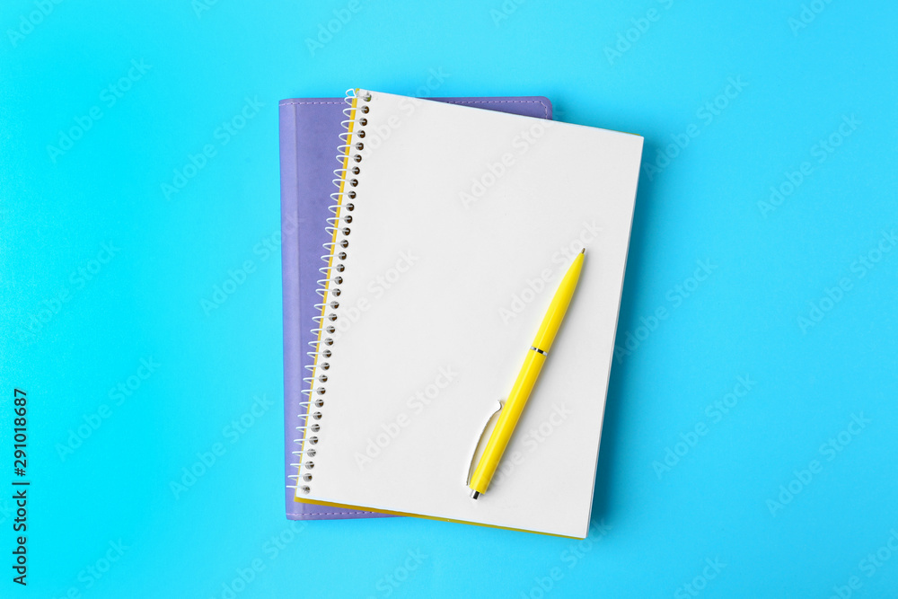 Notebooks and pen on light blue background, top view Notebooks and pen on light blue background, top view