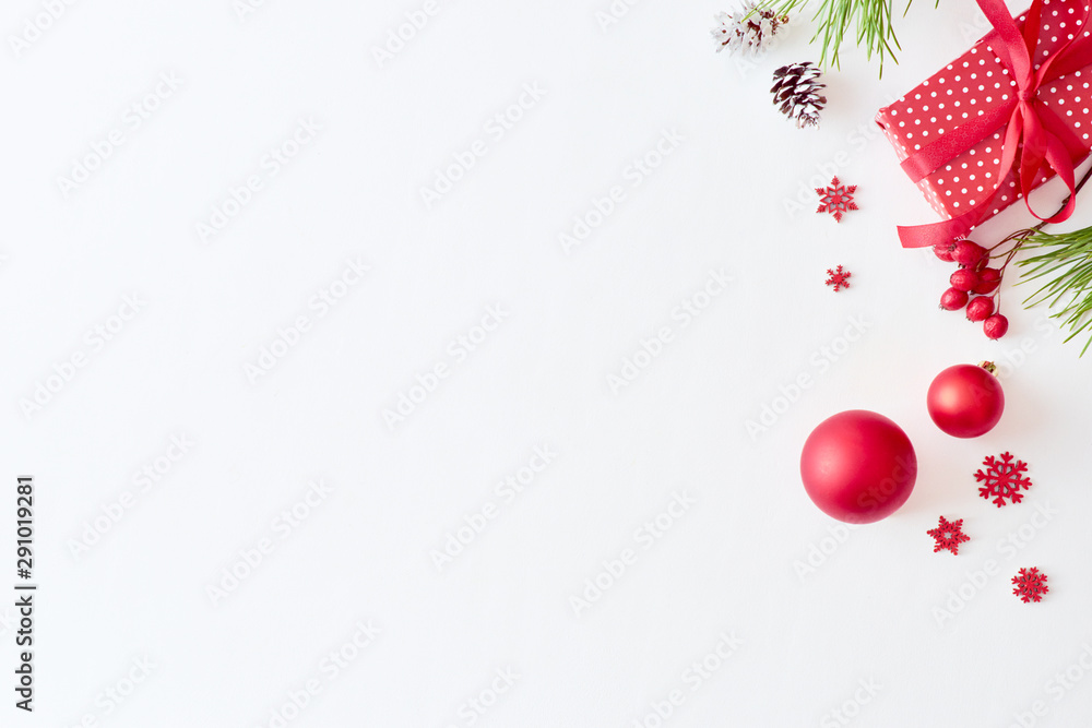 Flat lay christmas border with pine branche, balls and berries on a white background