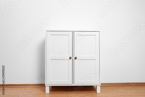 Wooden cabinet near white wall. Stylish home furniture