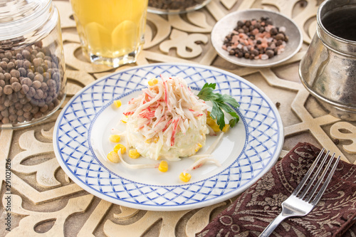 Crab salad with corn  cabbage on a plate and glass of lemonade on oriental wooden table