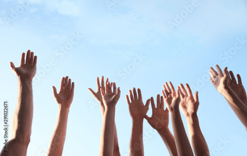 Group of volunteers raising hands outdoors, closeup