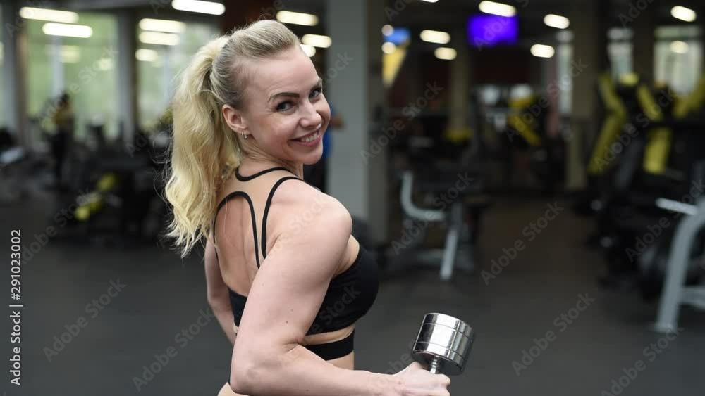 Portrait of young fitness woman smiling posing in gym. European caucasian female model in sportswear showing her muscles. Fitness coach trainer in health club Portrait of young fitness woman smiling posing in gym. European caucasian female model in sportswear showing her muscles. Fitness coach trainer in health club