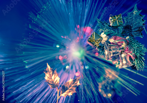 blue background with gleaming Christmas decorations on multicolored fireworks