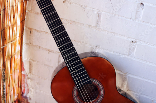 Music Concept: Brown acoustic guitar on a white wall. photo