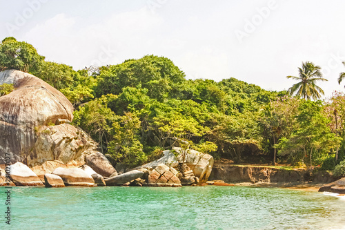 People in Caribbean beach with tropical forest in Tayrona National Park, Colombia. Tayrona National Park is located in the Caribbean Region in Colombia.