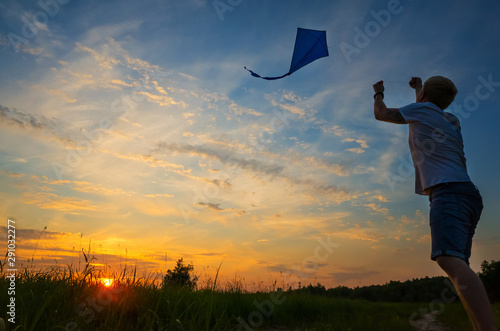 A young man launches a kite into the sky. Silhouette against sunset. photo