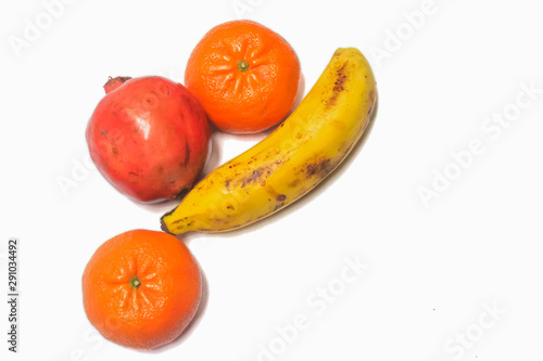 Pomegranate with banana and orange on white background