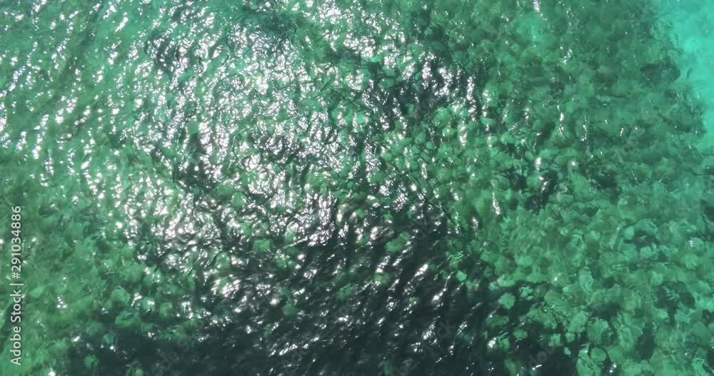 Aerial top view dolly shot of clear unpolluted turquoise sea with sun rays. Green seaweeds on the bottom. Summer holidays and vacation. Travel to the beach. Aerial top view dolly shot of clear unpolluted turquoise sea with sun rays. Green seaweeds on the bottom. Summer holidays and vacation. Travel to the beach.