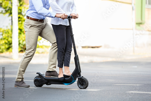 Smiling Young Couple Riding On Electric Scooter