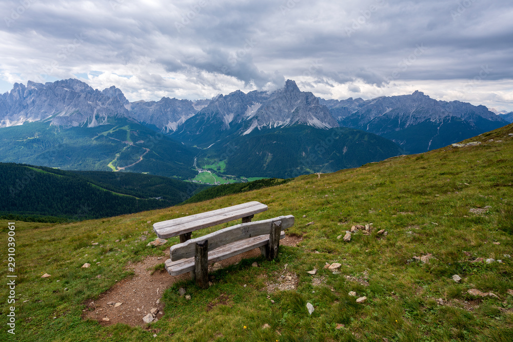 A bench in the meadow in mountains, Dolomites. Panoramic view on Dolomites