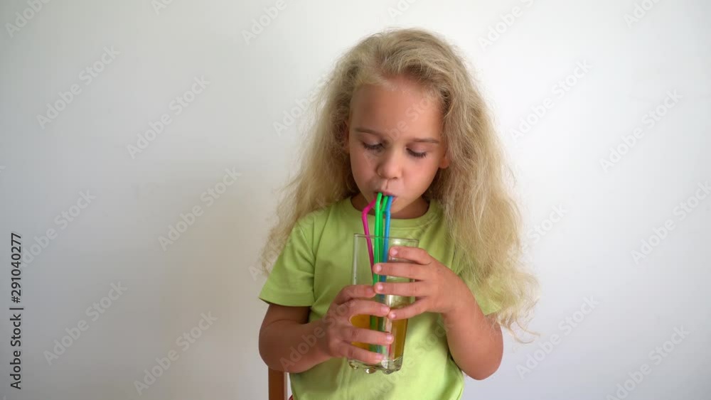 Playful female child drink apple juice from glass with straws. Gimbal motion Playful female child drink apple juice from glass with straws. Gimbal motion