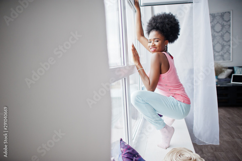 Young african american woman in pink singlet against window. Perfect morning.