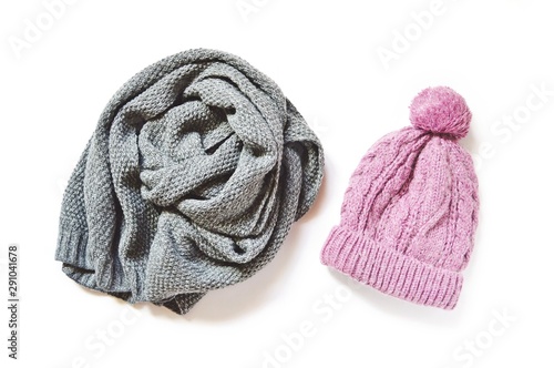 Gray woolen scarf and pink knitted hat on a white background. Flat lay photo winter clothes