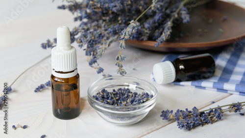 Fotografija two bottles with lavender oil and lavender flowers on a blue coverlet on a white