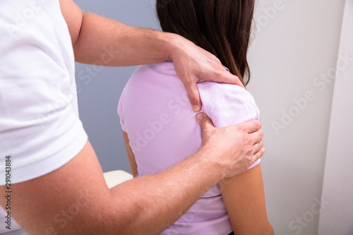 Male Physiotherapist Giving Shoulder Massage To Woman photo