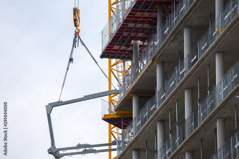 Crane hoisting block with hook on steel chain on the steel rope lift the huge steel beams. Loading\unloading of building materials on construction building site.