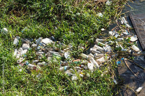 Closeup of bottles, bags and plastic trash floating in the water of Rio Tapajos surrounded by natural vegetation. Environment, pollution, plastic free, trash, recycling and conservation concept.