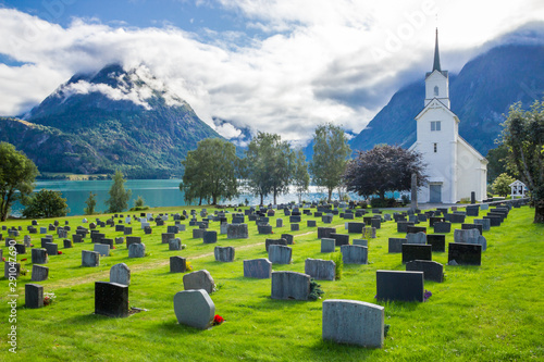 clouds over cemetery and church on Oppstrynsvatnet in the mountains in Norway photo