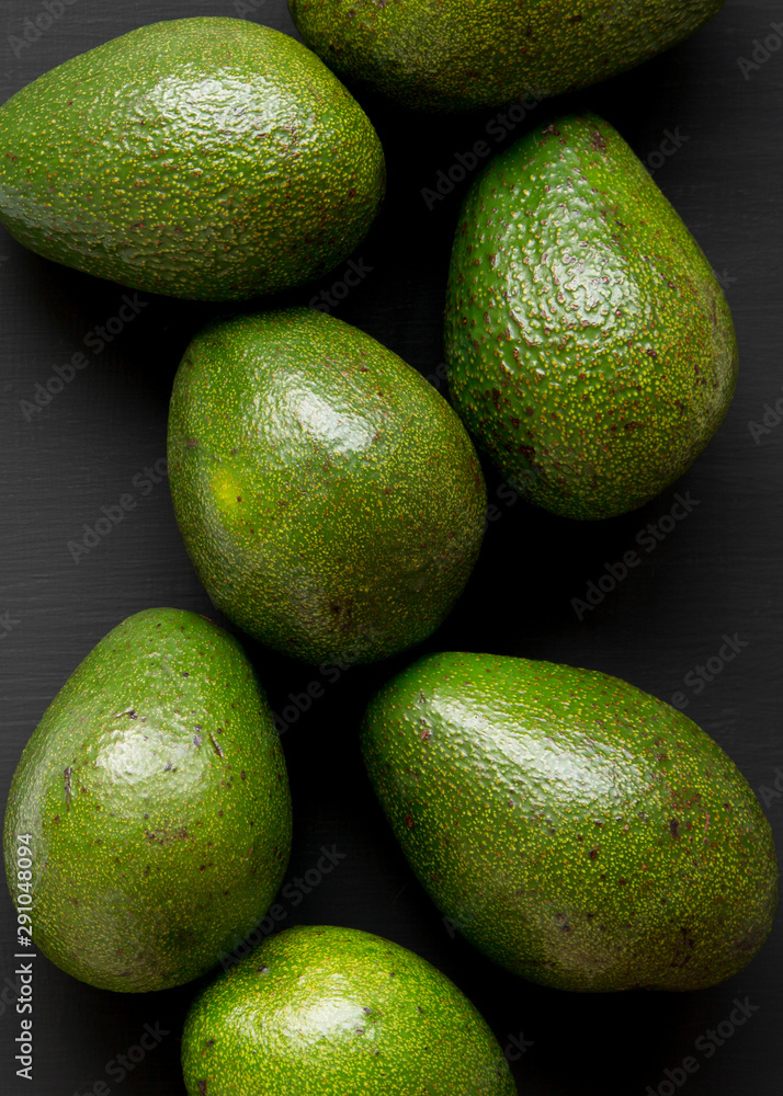 Whole avocados on a black surface, top view. Overhead, from above. Close-up. Whole avocados on a black surface, top view. Overhead, from above. Close-up.