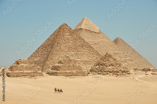 Tourists on camels are seeing Khufu  Khafre  Menkaure and pyramids of Queens