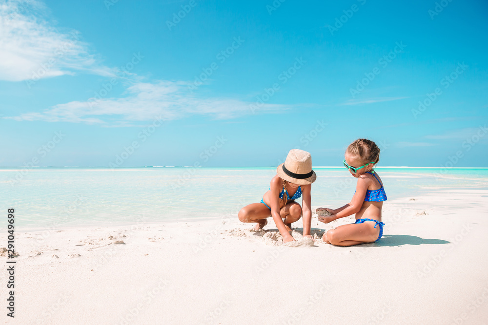 Two little happy girls have a lot of fun at tropical beach playing together