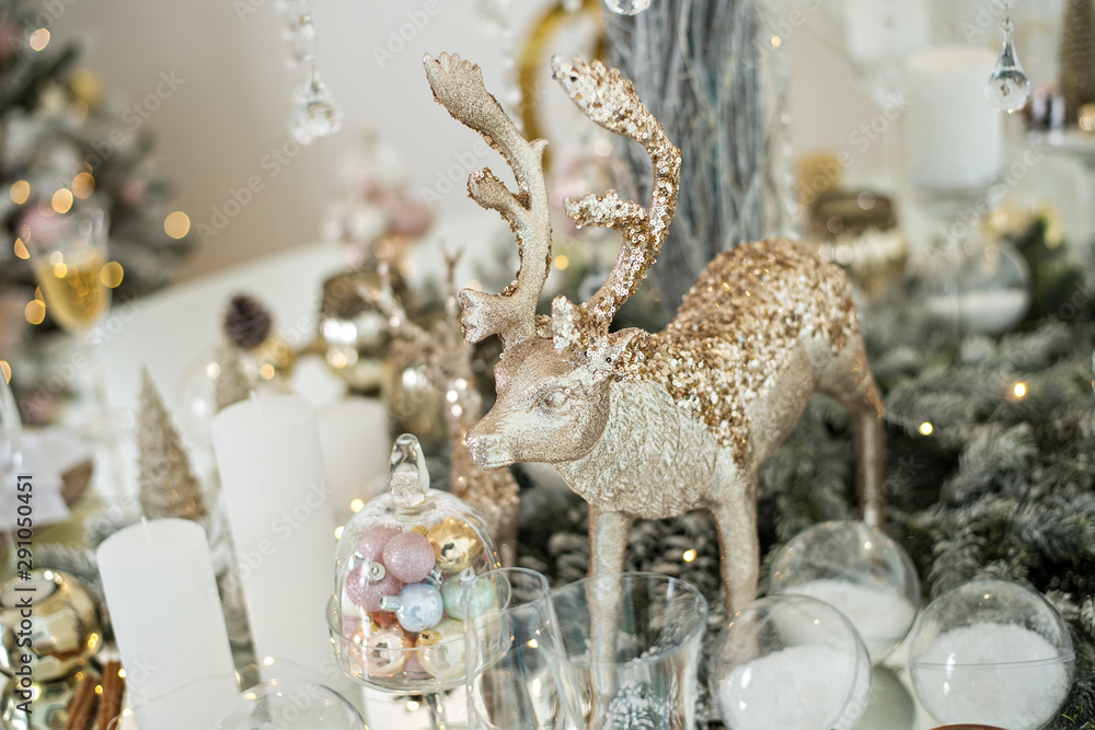 New Year's festive glass table setting. Greeting card. There are wine glasses and cutlery in the branches of the Christmas tree. Decorated with gold candles, deer, stars, balls. Copy space, bokeh fir New Year's festive glass table setting. Greeting card. There are wine glasses and cutlery in the branches of the Christmas tree. Decorated with gold candles, deer, stars, balls. Copy space, bokeh fir