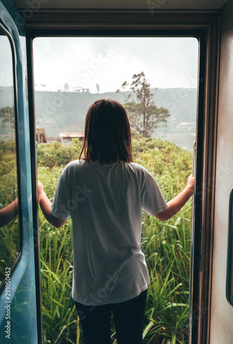 Young woman looking at the view through the door of a train