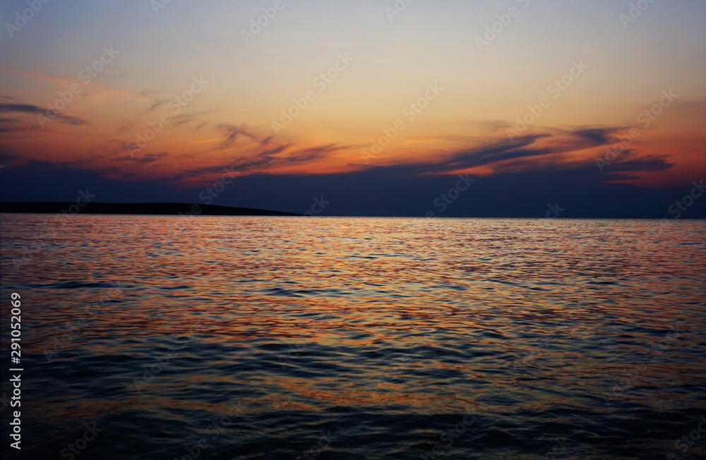Dusk at sunset on the horizon line with cloudy sky above wavy sea surface Dusk at sunset on the horizon line with cloudy sky above wavy sea surface