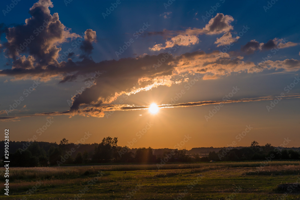 Fototapeta premium Rural landscape at sunset, clouds, fields, countryside, flares, grain in front, nature