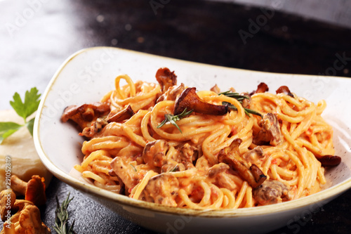 pasta with organic chanterelles. portion of spaghetti pasta with fried chanterelles in a creamy garlic sauce with cheese on a table