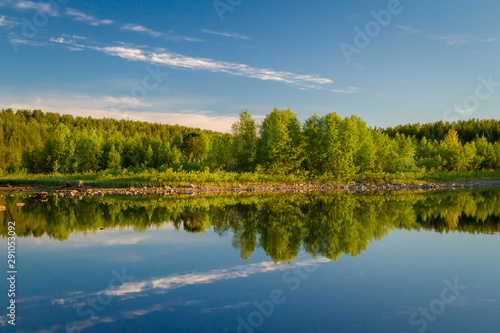 stones, crystal water and green trees on the lake Kovdozero in Zelenoborsky village near Kandalaksha. Kola Peninsula, Russia.