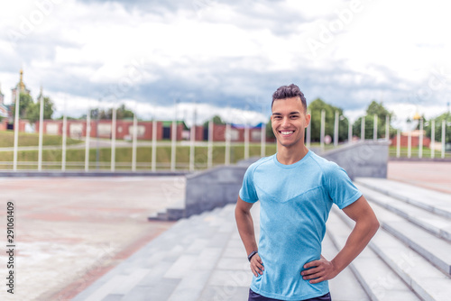 Handsome muscular athlete man smiles, looks carefully, close-up happy rejoices coach, summer city, sports shirt motivation youth lifestyle outdoor training. Motivation lifestyle. Free space for text.