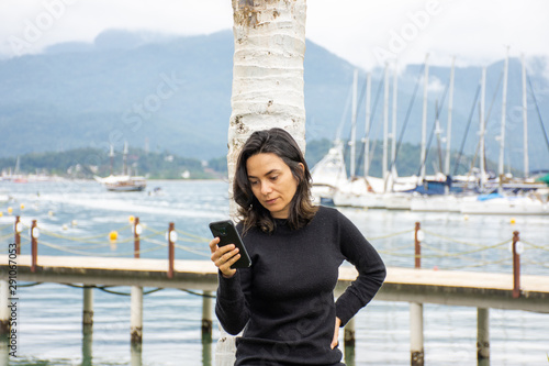 Woman use mobile phone in marina sailboats