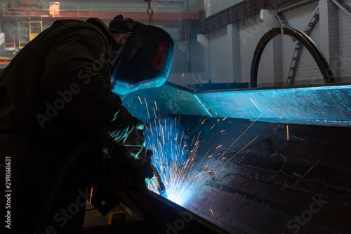 Industrial Worker at the factory welding closeup teal and orange sparks