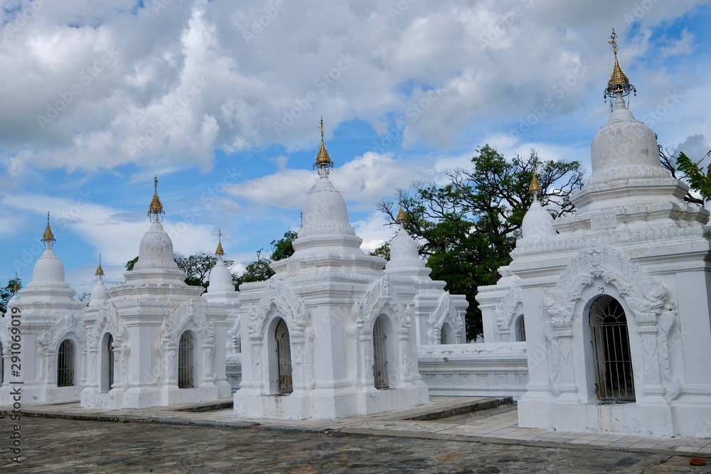 white stupa in Kuthodaw Pagoda, In Mandalay, Burma (Myanmar) with blue sky white clouds white stupa in Kuthodaw Pagoda, In Mandalay, Burma (Myanmar) with blue sky white clouds