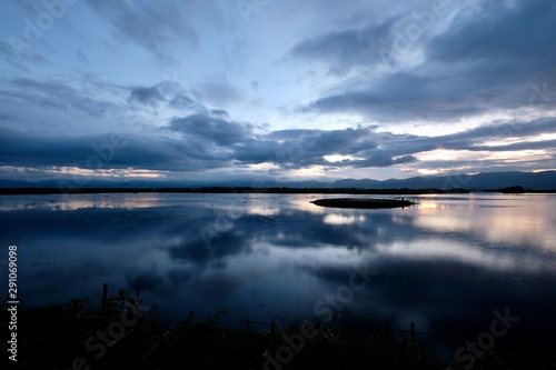 Beautiful sunset of Inle lake in Shan State of Myanmar. Peaceful water with cloudscape reflection. Wide angle © Robert