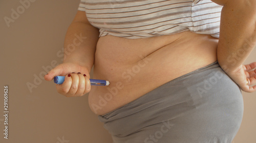 Obraz na płótnie Overweight woman applying diabetes medicine injection into her belly w salonie