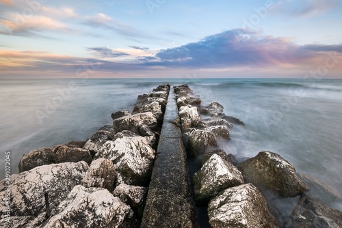Colorful sunset on a rocky pier extending to the horizon
